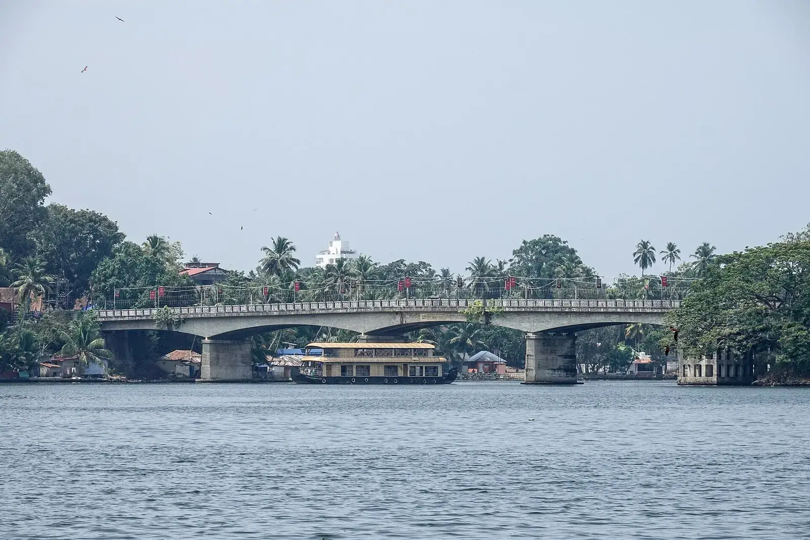 A houseboat on Ashtamudi Lake passing beneath the Thevally bridge at Kollam