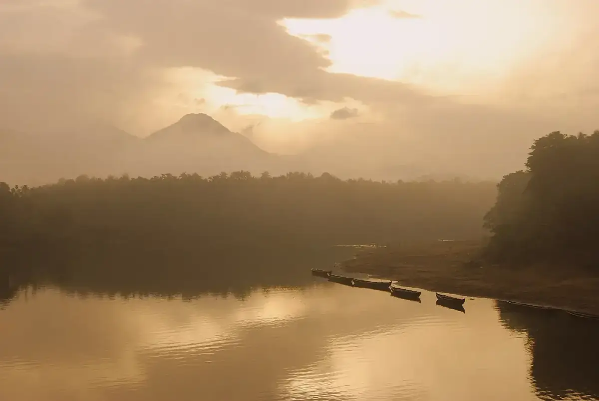 The Chaliyar river at Areekode at sunrise, with fishing boats moored along a sandbank and hills in the haze
